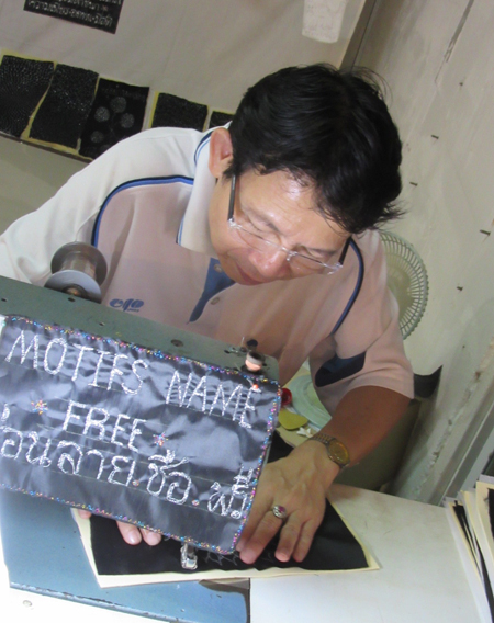 Embroiderer at river boat stop, Bangkok, Thailand