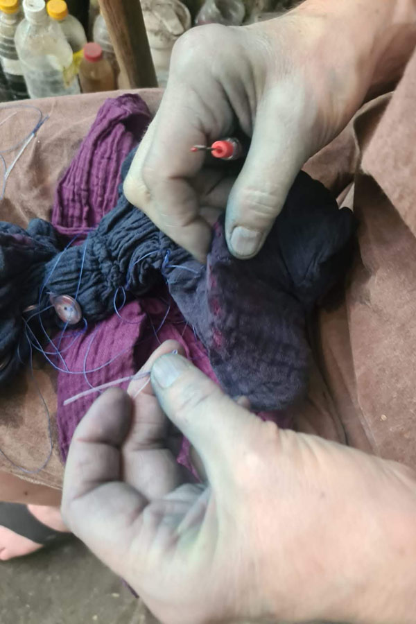 Picking apart shibori stitching after dyeing in indigo.