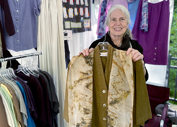 Rose holds up Sympatico designs at the LAMA Artisan Market in Ashland, Oregon