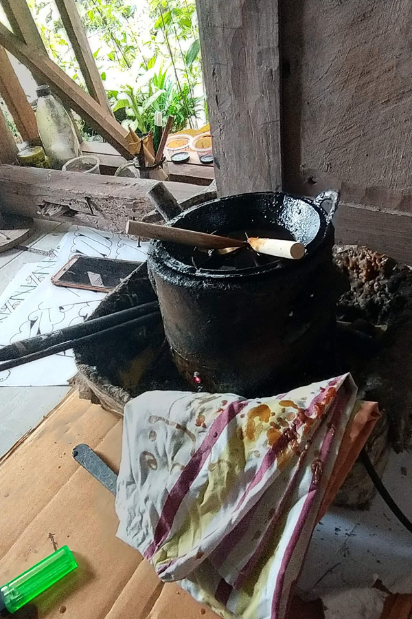 A pot of wax on the stove, brushes and tjanting tools for making batik
